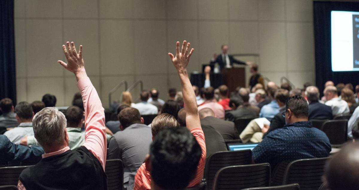Attendees raising their hands to ask questions during a Q&A session
